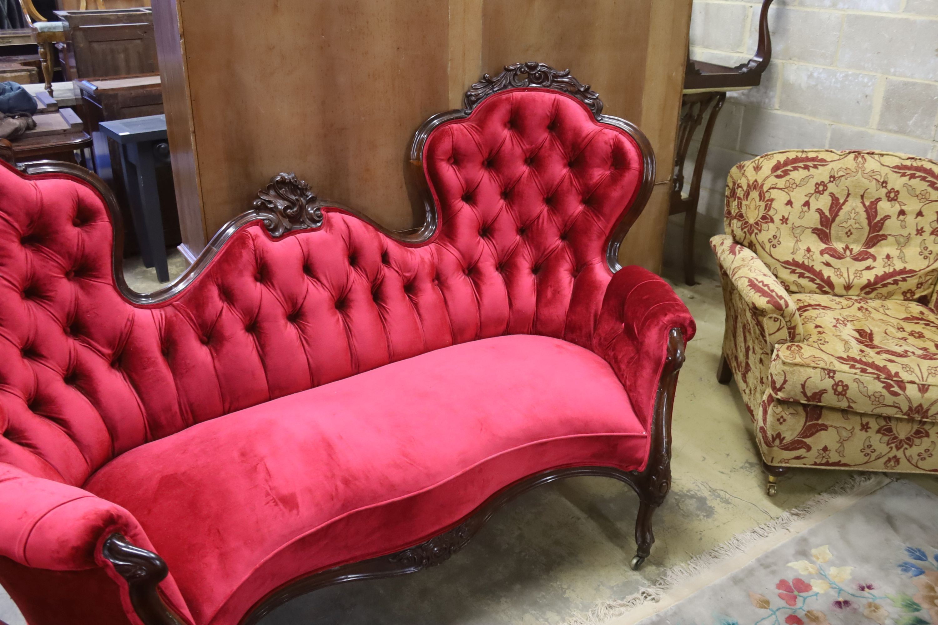 A Victorian carved rosewood double spoon back settee upholstered in deep buttoned scarlet velvet, length 200cm, depth 96cm, height 122cm